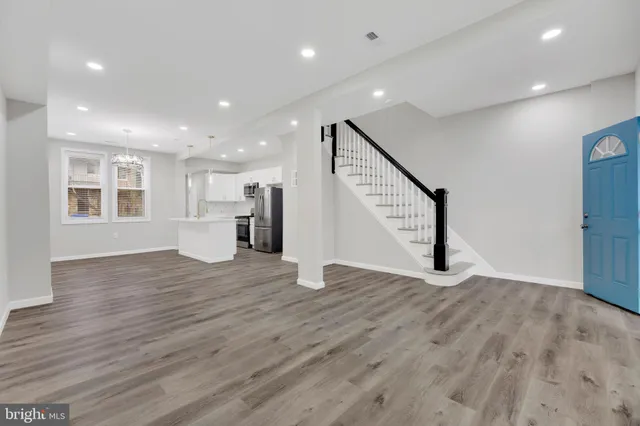 a view of an empty room with wooden floor and stairs