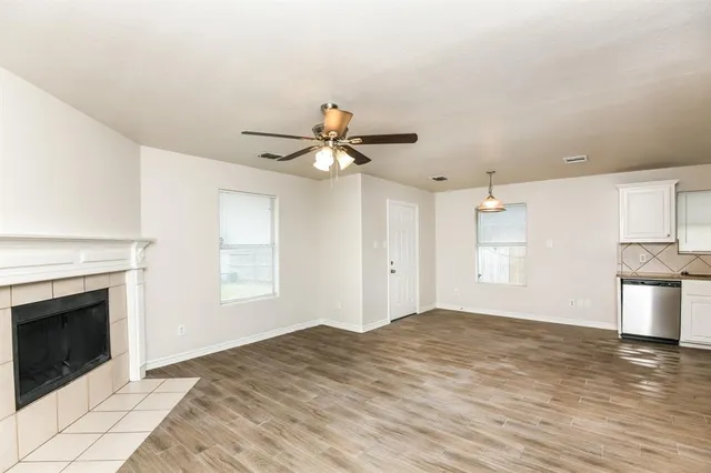 a view of a livingroom with a fireplace a ceiling fan and wooden floor
