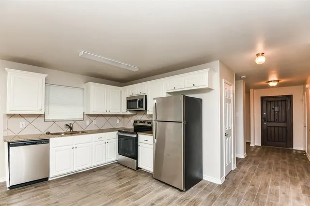 a kitchen with a refrigerator a sink and dishwasher with wooden floor