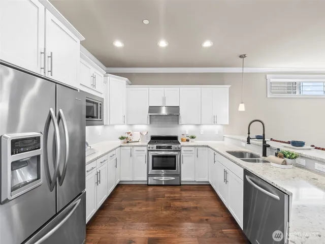 a kitchen with stainless steel appliances granite countertop a stove top oven a sink and a refrigerator