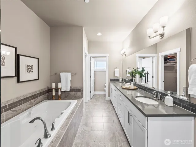 a bathroom with a granite countertop double vanity sink a bathtub and shower