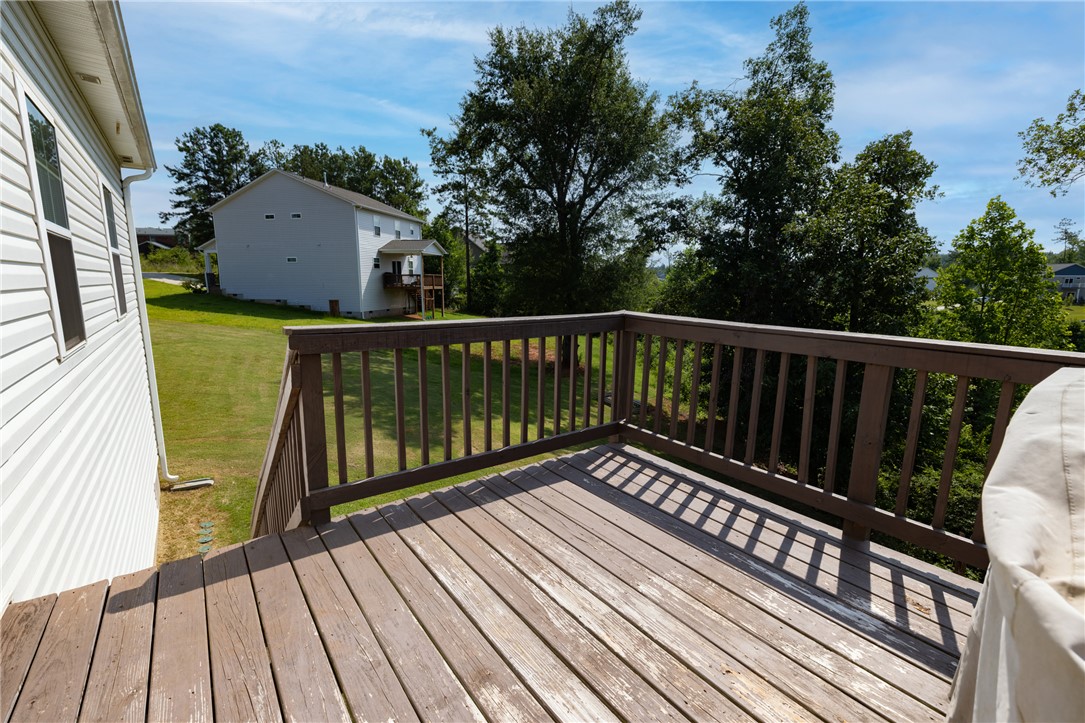 768 Rocky Ridge Circle Seneca, SC 29678 - Photo 23 of 30 A spacious wooden deck extends outward, offering elevated views of the verdant yard and distant structures.