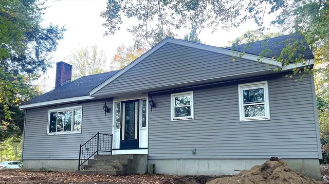 a front view of a house with a tree