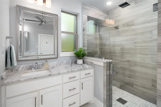 a bathroom with a granite countertop sink a mirror and a shower