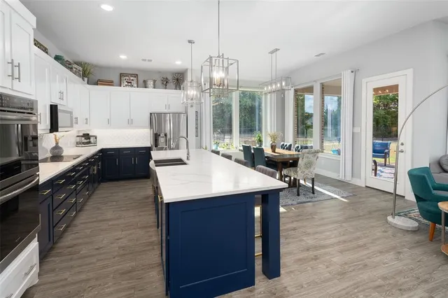 a kitchen with stainless steel appliances granite countertop a table chairs stove and wooden floor
