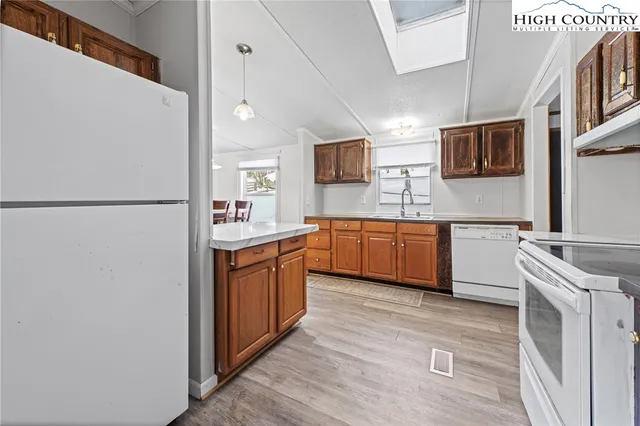 a kitchen with stainless steel appliances granite countertop a refrigerator a sink a stove top oven a counter space and cabinets