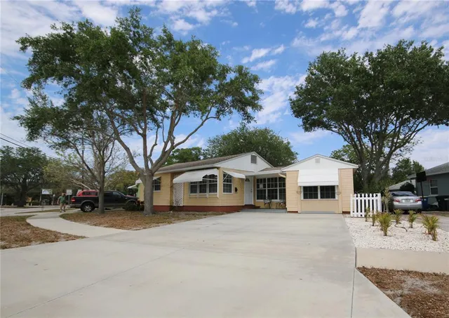 a view of a white house with a large tree