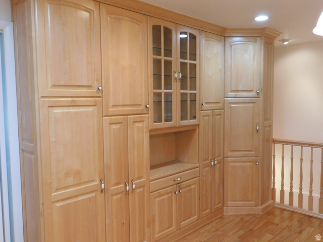 2148 Carolyn Way Bountiful, UT 84010 - Photo 6 of 40 Built-in light wood cabinetry featuring glass-front display cabinets, various storage configurations, a recessed lighting fixture, and light wood-finish flooring