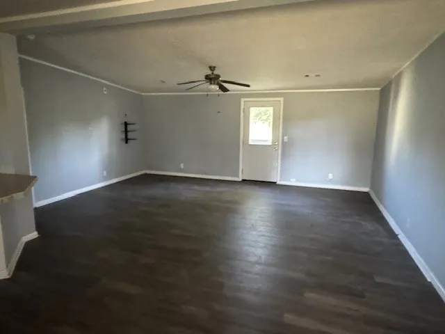 an empty room with wooden floor fan and windows