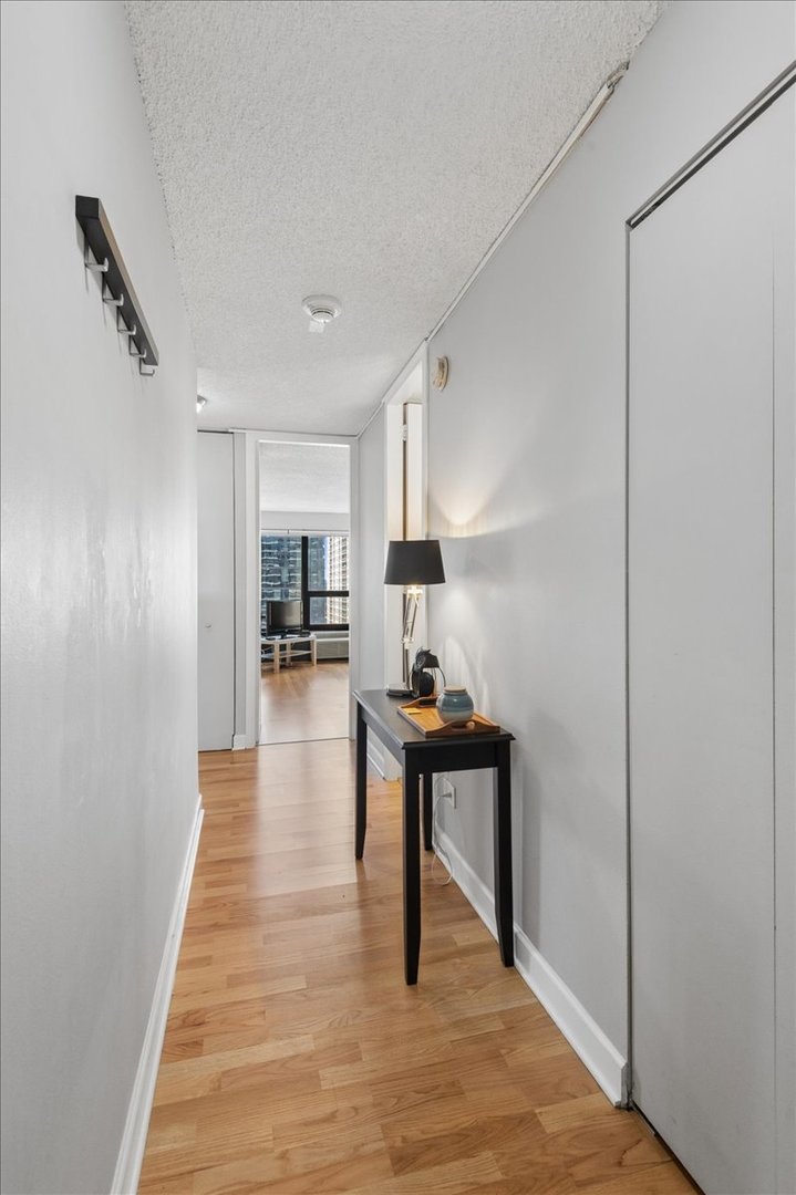 30 East Huron Street, Unit 2204 Chicago, IL 60611 - Photo 2 of 36 a hallway with wooden floor table and chairs