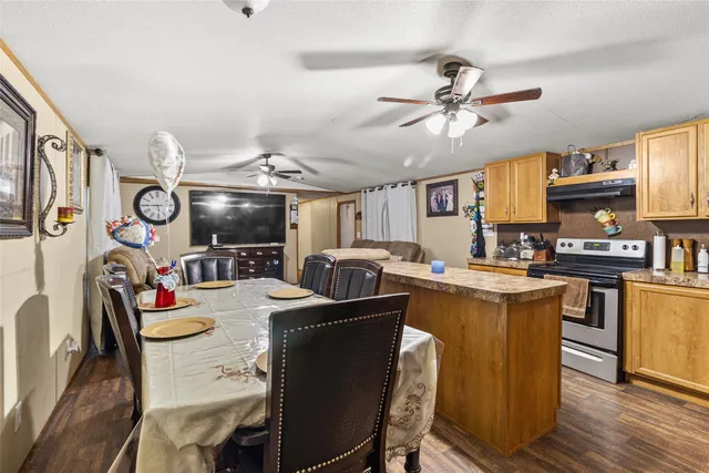 a kitchen with stainless steel appliances kitchen island granite countertop a table chairs stove and cabinets