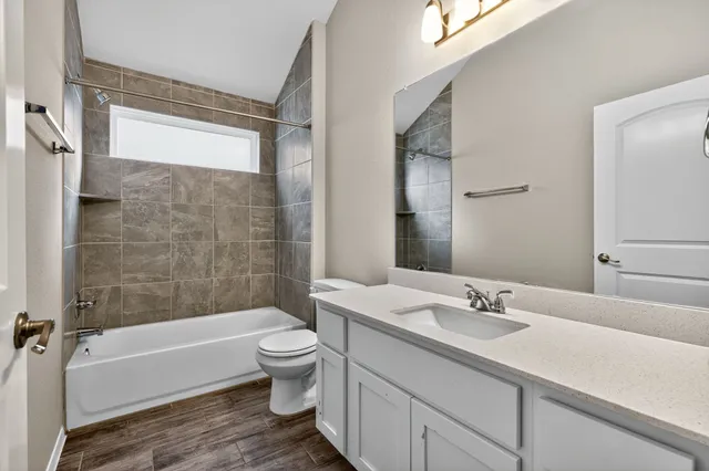 a bathroom with a bathtub shower sink vanity mirror and toilet