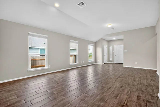 a view of an empty room with wooden floor and windows