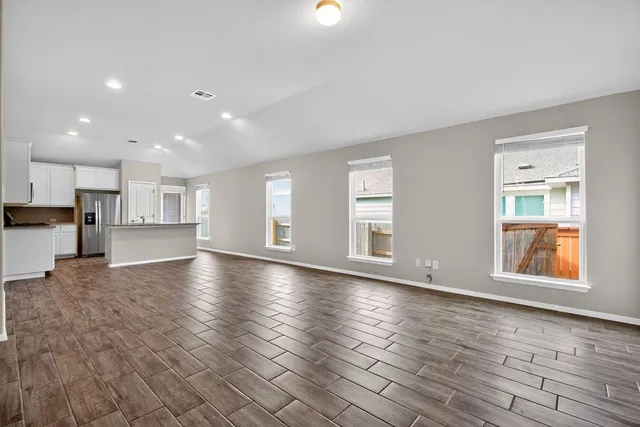 a view of empty room with kitchen and window