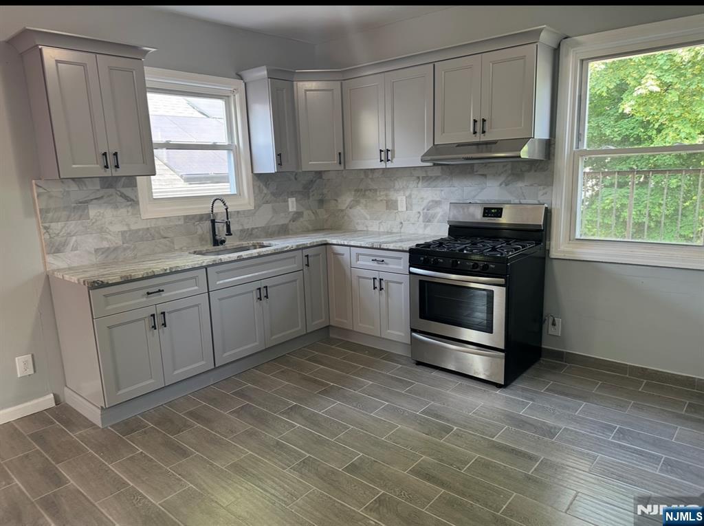 a kitchen with stainless steel appliances granite countertop a stove a sink and white cabinets