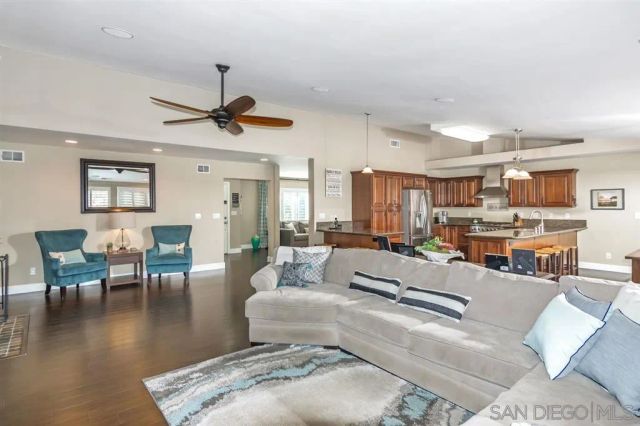 a living room with furniture kitchen view and a wooden floor