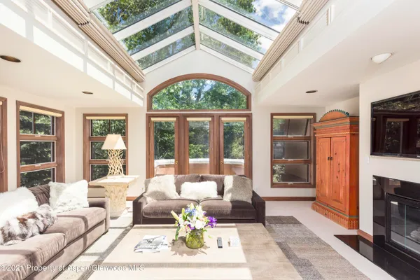 a living room with furniture a fireplace and floor to ceiling windows