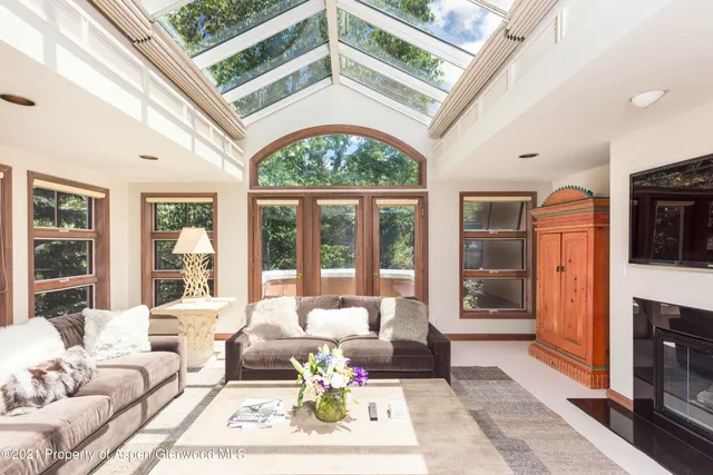 a living room with furniture a fireplace and floor to ceiling windows