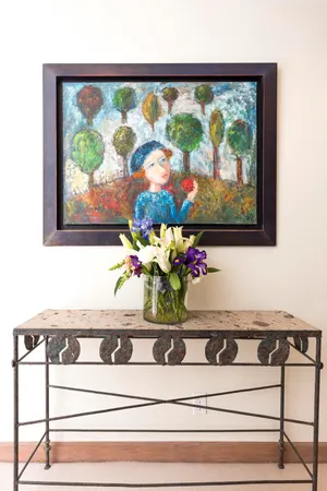 a sink with a painting on the wall and a potted plant