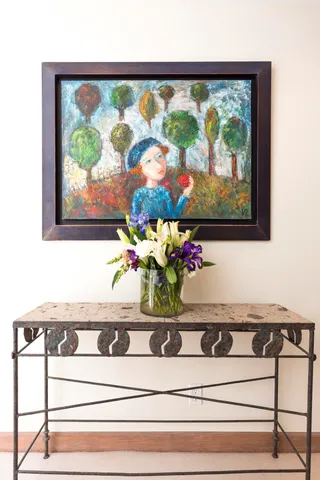 a sink with a painting on the wall and a potted plant