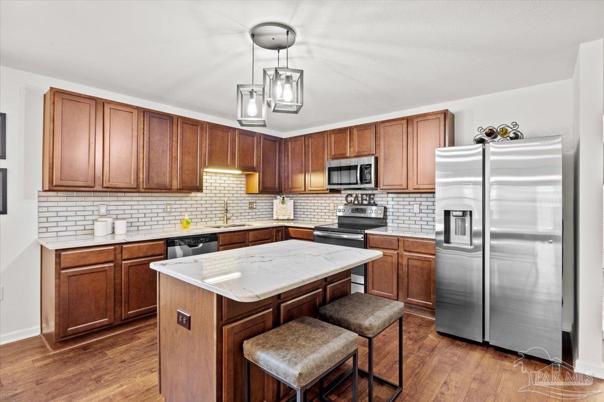 3473 Quail Drive Pace, FL 32571 - Photo 11 of 38 a kitchen with a refrigerator a sink a stove a microwave cabinets and chairs