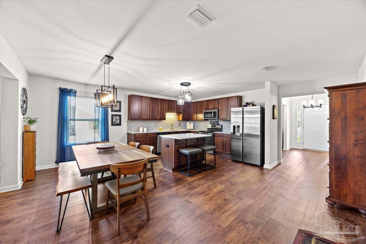 3473 Quail Drive Pace, FL 32571 - Photo 12 of 38 a kitchen with a refrigerator a dining table and chairs