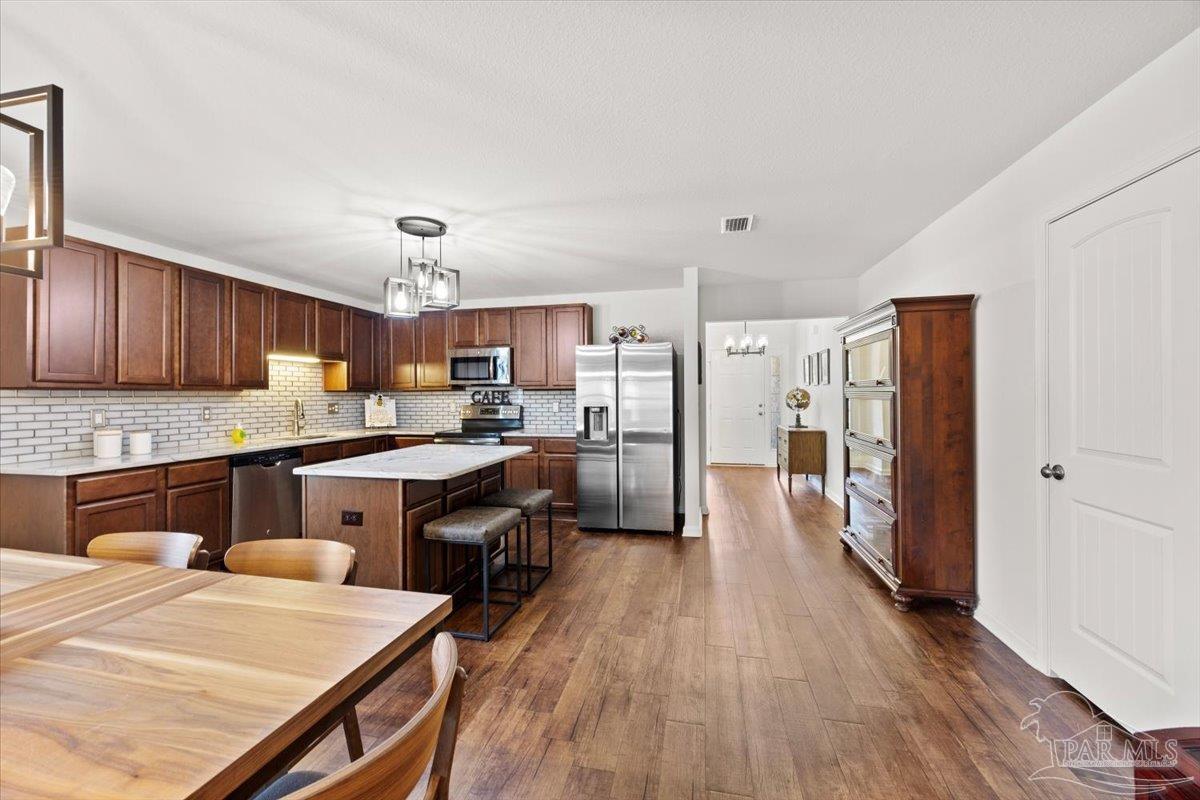 3473 Quail Drive Pace, FL 32571 - Photo 13 of 38 a kitchen with stainless steel appliances sink refrigerator dining table and chairs