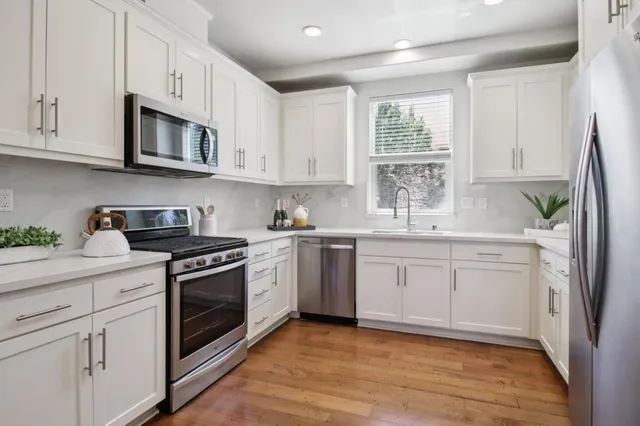 a kitchen with stainless steel appliances granite countertop a refrigerator sink and white cabinets