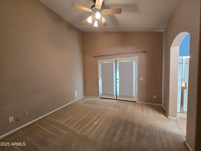 an empty room with closet and a chandelier fan