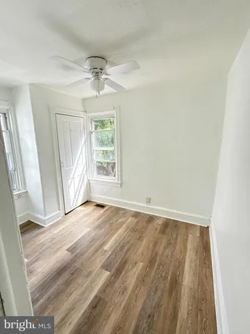 an empty room with wooden floor exposed radiator and windows