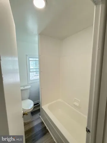 a bathroom with a granite countertop toilet and a bathtub