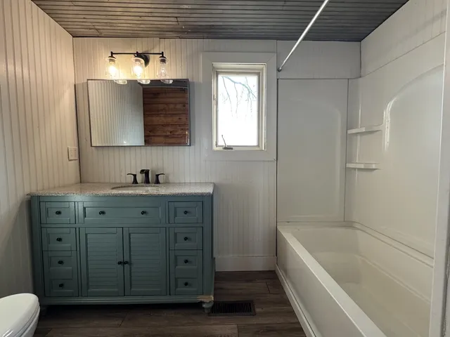 a bathroom with a tub a sink and mirror