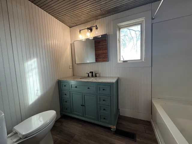 a bathroom with a granite countertop sink toilet a large mirror a bathtub and shower