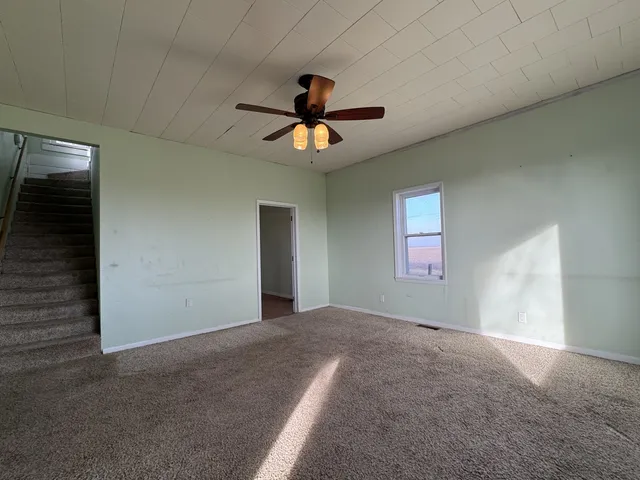 a view of a livingroom with a chandelier fan and windows