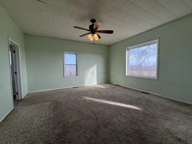 an empty room with windows and fan