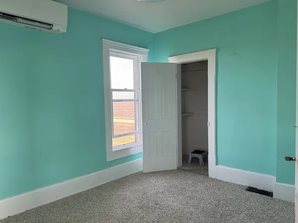 a view of an empty room with closet and a window