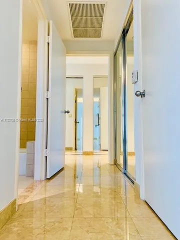 a view of a hallway with wooden floor and a bathroom