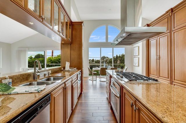 a kitchen with stainless steel appliances granite countertop a sink a stove and a wooden floors