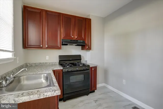 a kitchen with granite countertop a sink stove and cabinets