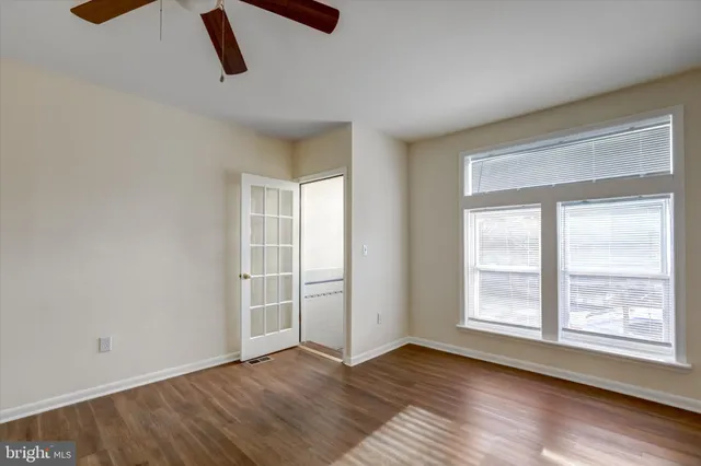 a view of an empty room with wooden floor and window
