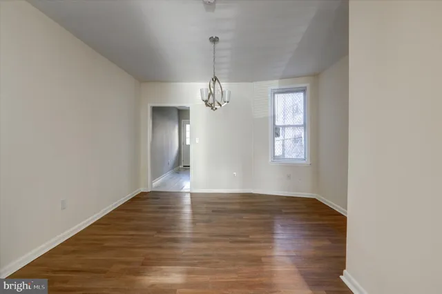 a view of a room with wooden floor chandelier and windows