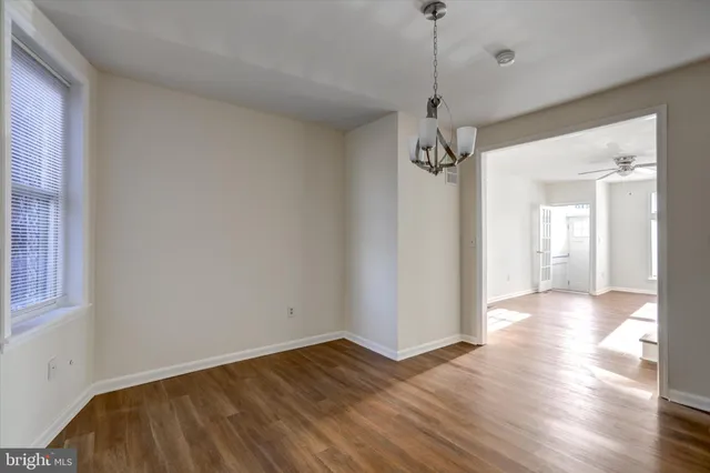 a view of a hallway with wooden floor and a chandelier