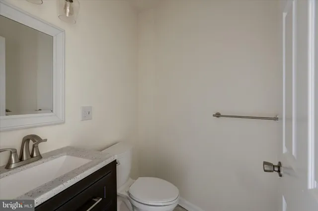 a bathroom with a granite countertop toilet sink and mirror