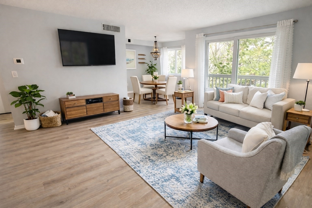 8 Beal's Cove Road, Unit K Hingham, MA 02043 - Photo 1 of 10 a living room with furniture a flat screen tv and a large window