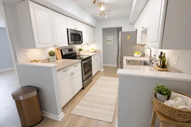 a kitchen with stainless steel appliances a white cabinets wooden floors and a sink