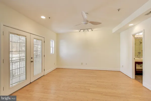 an empty room with chandelier fan and windows