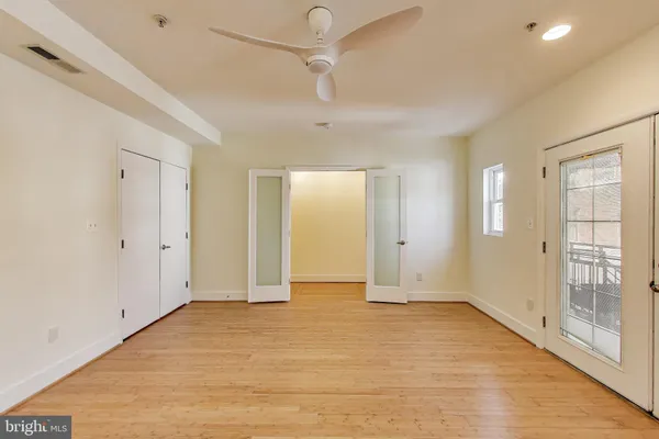 a view of an empty room with wooden floor and a window