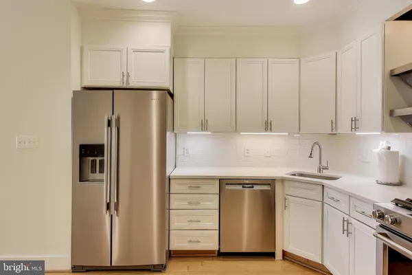 a kitchen with stainless steel appliances white cabinets and a refrigerator