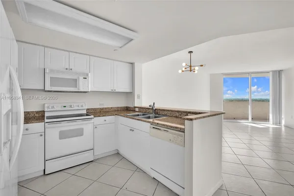 a kitchen with granite countertop white cabinets and white appliances