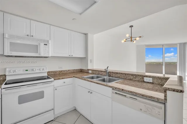 a kitchen with granite countertop white cabinets and white appliances